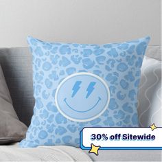 a blue pillow sitting on top of a couch next to a gray pillow with an image of a smiling face