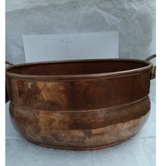 a large metal bowl sitting on top of a piece of paper next to a white envelope