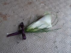 a flower that is laying on the ground next to a knife with some grass sticking out of it