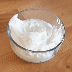 a glass bowl filled with whipped cream on top of a wooden table