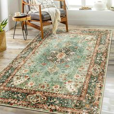 a green rug with an ornate design on the floor in front of a chair and window