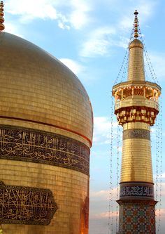 two tall buildings with gold and black designs on them, one has a clock tower in the background