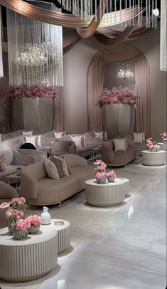 a room filled with lots of couches and tables covered in pink flowers on top of them