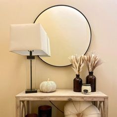 a table with some vases and a mirror on top of it next to a lamp