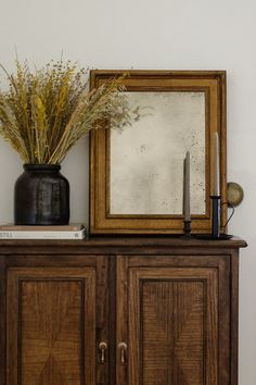 a wooden cabinet with a mirror and vase on top