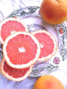 three grapefruits and two oranges on a plate