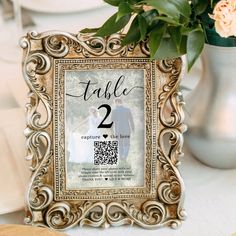 a wedding table number frame sitting on top of a table next to a vase filled with flowers