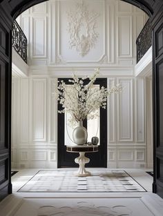 a vase filled with white flowers sitting on top of a table in front of a doorway