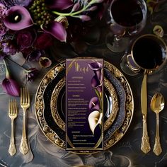 a place setting with purple flowers and silverware on a black table cloth in front of a menu