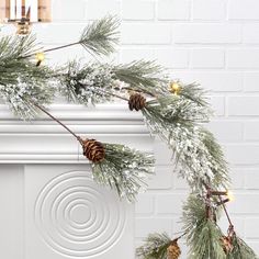 a white fireplace with pine cones and lights