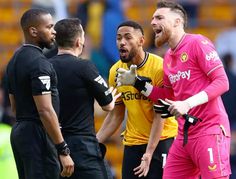 three soccer players are talking to each other in the middle of a game, with one holding his mouth open