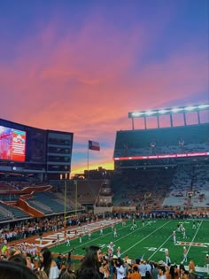 a football stadium filled with lots of people watching the sun go down in the distance