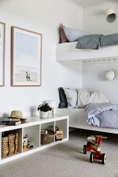 a bedroom with bunk beds and toys on the floor next to each other in front of two framed pictures