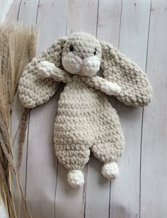 a crocheted stuffed animal laying on top of a wooden floor next to dry grass