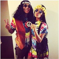 two people dressed up in hippie clothing posing for the camera with peace signs on their fingers