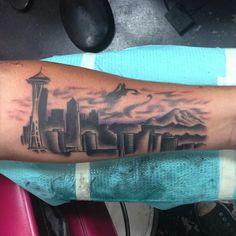 a person with a tattoo on their arm that has a cityscape in the background