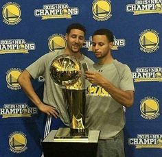 two men standing next to each other holding a trophy