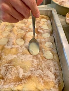 a person spooning some food out of a pan with powdered sugar on it