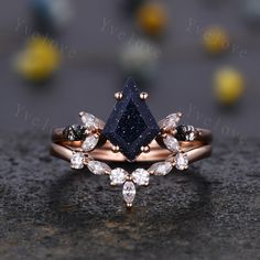 a diamond and blue sapphire engagement ring set on top of a black stone surface with yellow flowers in the background