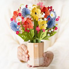 a person holding a paper flower bouquet in their hands