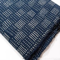 the blue and white fabric is folded up on top of another piece of cloth with fringes