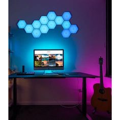 a desktop computer sitting on top of a wooden desk in front of a purple light