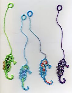 three different colored seahorses are hanging from strings on a white surface, one is blue and the other is green