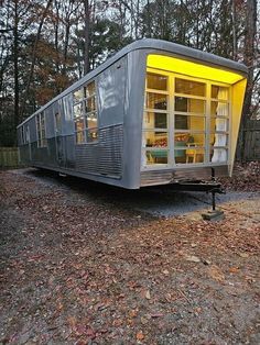 a small house that is sitting in the middle of some leaves on the ground and it's lit up with yellow lights