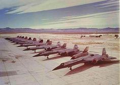 a row of fighter jets parked on top of an airport tarmac