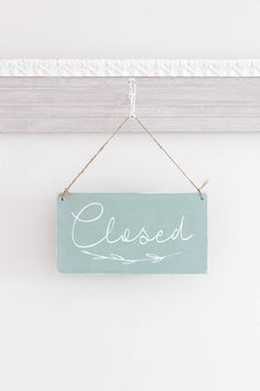 a sign hanging on the wall that says closed with white paint and string attached to it