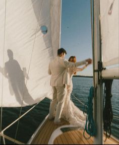 a man and woman standing on the deck of a sailboat