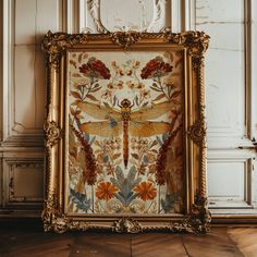 an ornate gold frame with a dragonfly painted on it in front of a wall