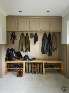 a wooden bench with shoes and coats hanging on the wall