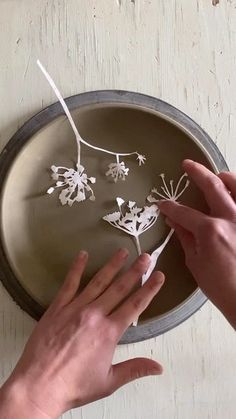 two hands reaching for paper flowers on a tray