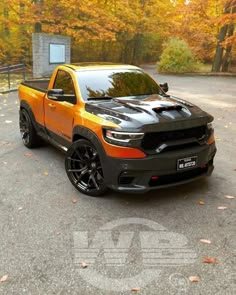 an orange and black truck parked on the side of a road in front of trees