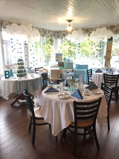 a dining room with tables and chairs covered in white tablecloths, decorated with balloons