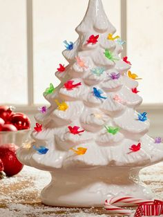 a white ceramic christmas tree with birds and candy canes on the table next to it