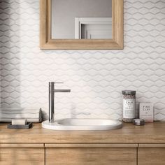 a bathroom sink sitting under a mirror on top of a wooden counter next to a cabinet