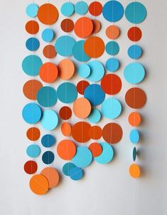 an art piece made out of circles on a white wall with blue, orange and red paper