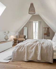 an attic bedroom with white linens and natural wood flooring is featured in this post