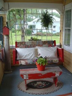 a porch with a couch, table and potted plant on the front porch area