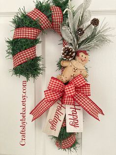 a christmas wreath with a gingerbread man and pine cones hanging on the front door