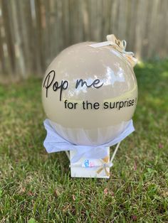 a balloon with the words pop me for the surprise on it sitting in the grass