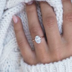 a close up of a person's hand with a diamond ring on their finger