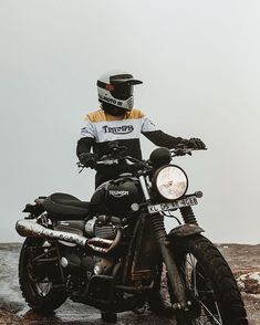 a man sitting on top of a motorcycle in the rain wearing a helmet and gloves