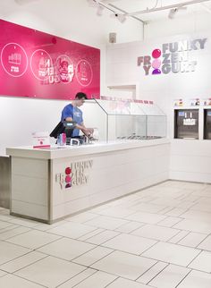 an ice cream sundae with raspberries on top and a man behind the counter