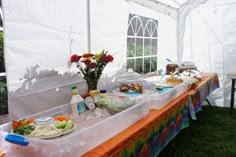 a table covered with food and drinks under a white tent