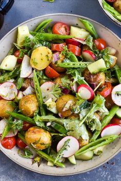 a salad in a bowl with potatoes, radishes and other veggies