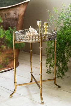 a gold tray with candles on it next to a potted plant