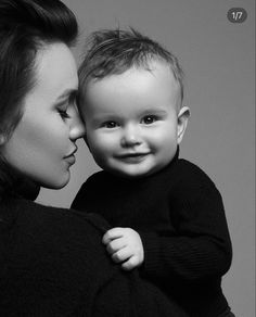 a black and white photo of a woman holding a baby